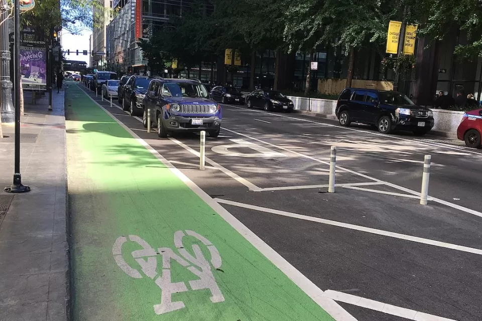 Green painted bike lane protected by rown of parking.